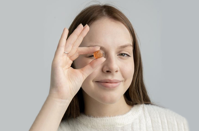 A woman puts femometer vitamin gummie before her eyes